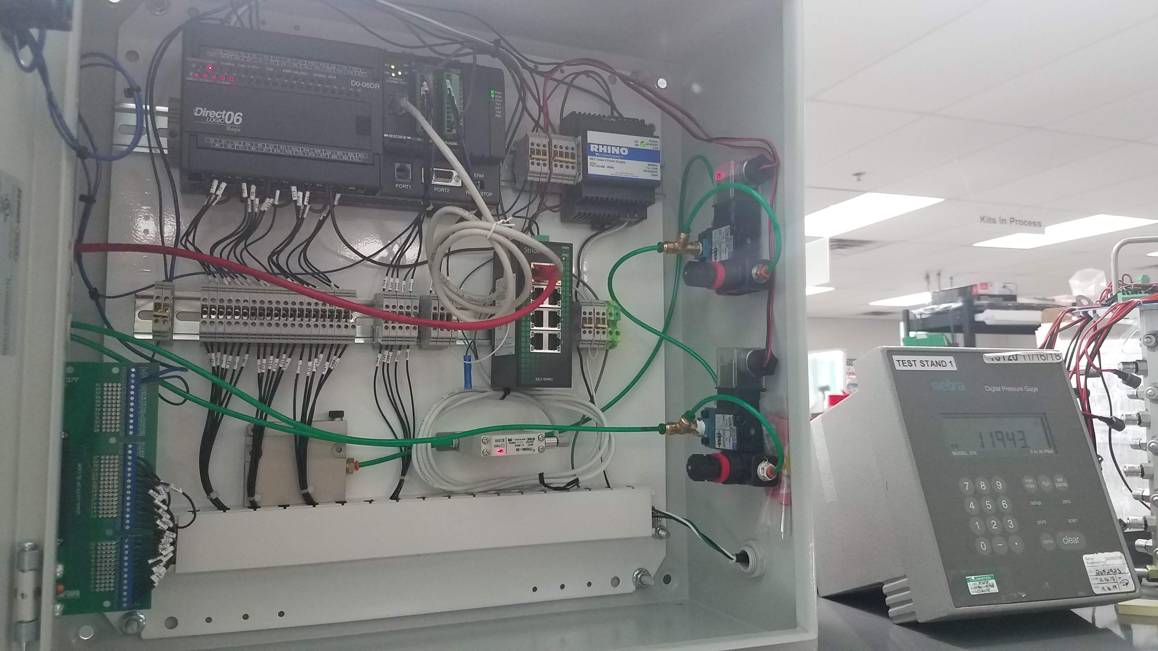 Control enclosure with PLC, wiring, and communication hardware for switch validation